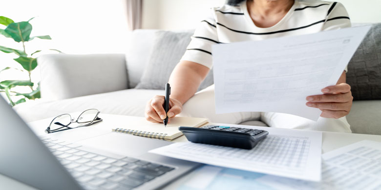 Woman is calculating annual tax with calculator and filling form